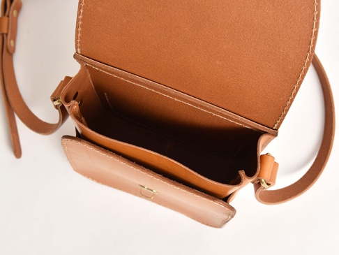 職人手作皮革翻蓋迷你單肩包，採用天然棕褐色皮革製成，設計簡約，展示包體內側隔層與黃銅色金屬鎖扣。