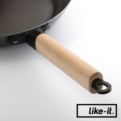 特寫鏡頭展示了黑色鐵鍋的木質手柄，鍋身邊緣有金屬固定件，手柄末端有一個掛環。