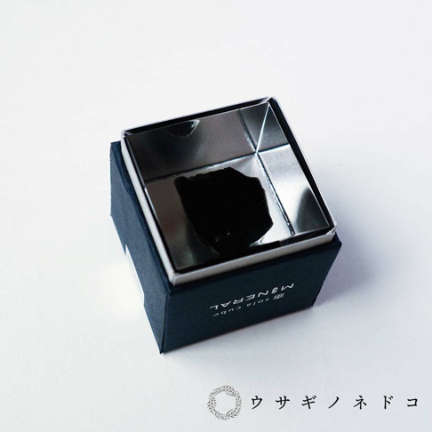 Sola cube Mineral 礦石立方塊，內含不規則黑色礦石，置於銀色鏡面立方體中，外盒為深藍色紙盒，印有白色「MINERAL sola cube」字樣。