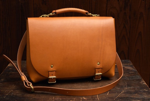 職人手作皮革雙扣兩用側背包 (CW-137) M，採用淺棕色皮革製成，設有金色雙扣和可調節的皮革肩帶，另有頂部提把。