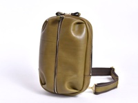 橄欖綠皮革立體運動斜背包，側面有拉鍊，搭配可調節的深棕色織帶和金色金屬扣環。