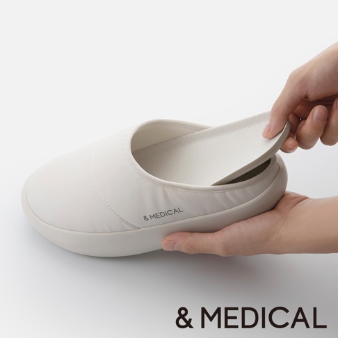 &MEDICAL 標誌的淺色拖鞋，一隻手正在取出鞋墊，展示其構造。