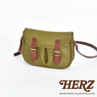 橄欖綠皮革製成的傳統釣魚包，配有可調節的深棕色皮革肩帶和兩個帶有黃銅扣環的翻蓋。