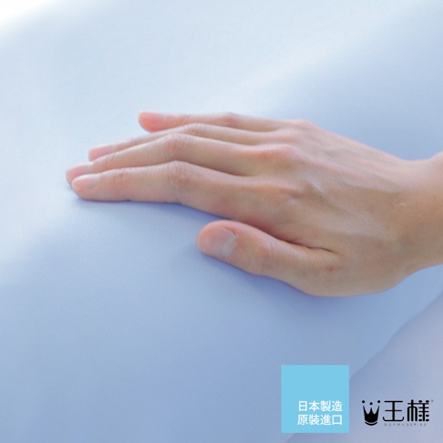 一隻手輕柔地放在淺藍色的「王樣の舒涼枕」上，枕頭表面光滑，材質看起來柔軟。