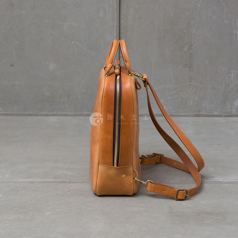職人手作皮革Organ商務後背包，側邊視角，淺棕色牛皮材質，具有拉鍊開合與可調節肩帶。