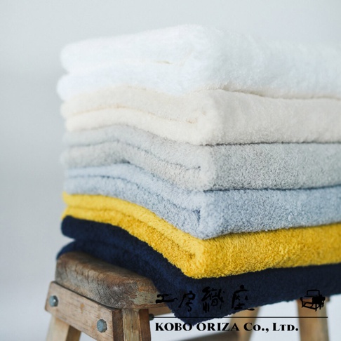 一疊不同顏色的超細纖維浴巾，包括白色、米色、淺灰、淺藍、黃色和海軍藍。