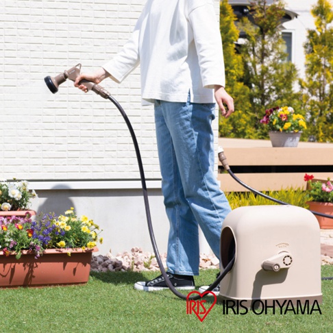 淺米色圓潤造型的家用全覆蓋水管車，設有米色捲軸手柄，連接黑色軟管，用於庭院澆水。