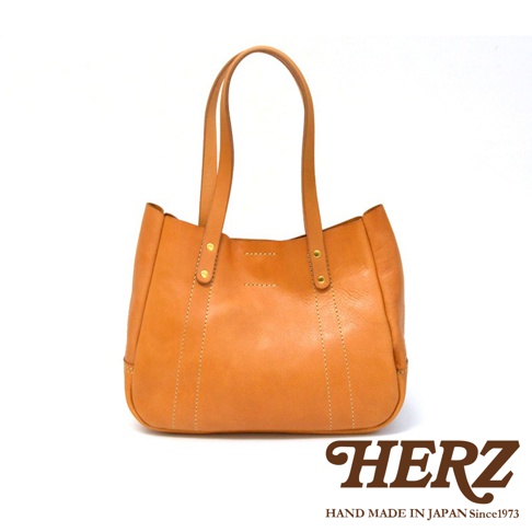 一只棕褐色的皮革仕女托特包，有兩個提把，包身有縫線裝飾，底部為圓弧形。