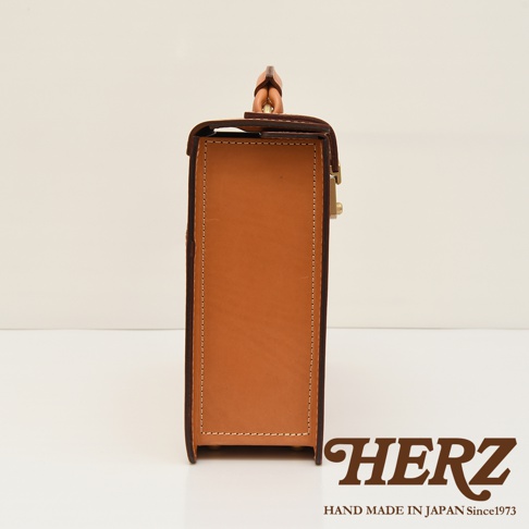 職人手作皮革機師箱，側視圖，呈現其堅挺的方形輪廓，棕褐色皮革材質，搭配金屬鎖扣，縫線整齊，風格簡約。