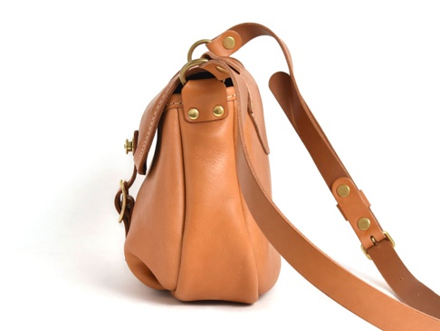 職人手作皮革休閒旅行馬鞍包 (CK-20)，這款馬鞍包採用天然棕色皮革製成，設有可調節的長肩帶和金屬扣。包身線條流暢，結構穩固，展現出簡約而實用的設計風格。