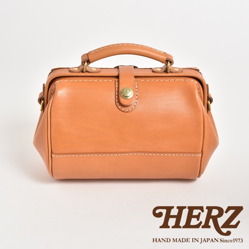 職人手作皮革口金醫生單肩包，採用天然棕色皮革，配有金色口金扣和縫線細節，設有手提把和可拆卸肩帶。