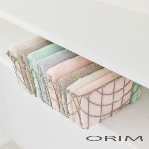 金屬網籃內整齊擺放著多條柔軟的浴巾，顏色包含粉紅色、淡灰色、淺綠色、米白色和卡其色。