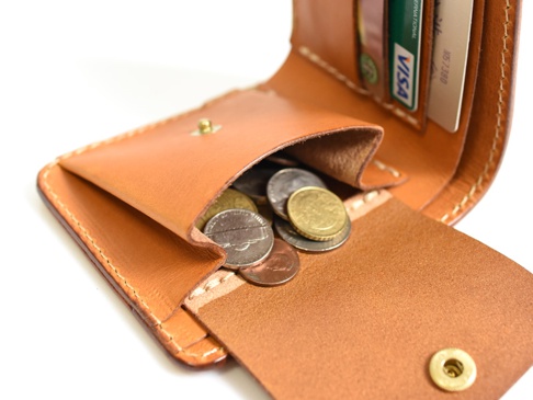 職人手作皮革經典掀蓋扣式雙折短夾，採用天然棕色皮革製作，內含零錢袋，裝有硬幣，並有信用卡插槽。