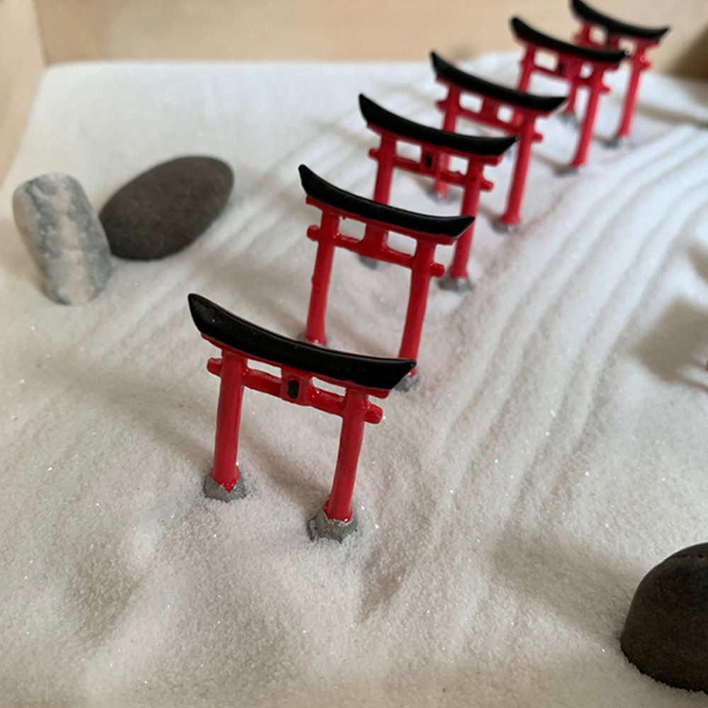 日本枯山水模型，紅白色鳥居，點綴著黑色石塊，置於細緻的白色砂石上，營造日式庭園景觀。