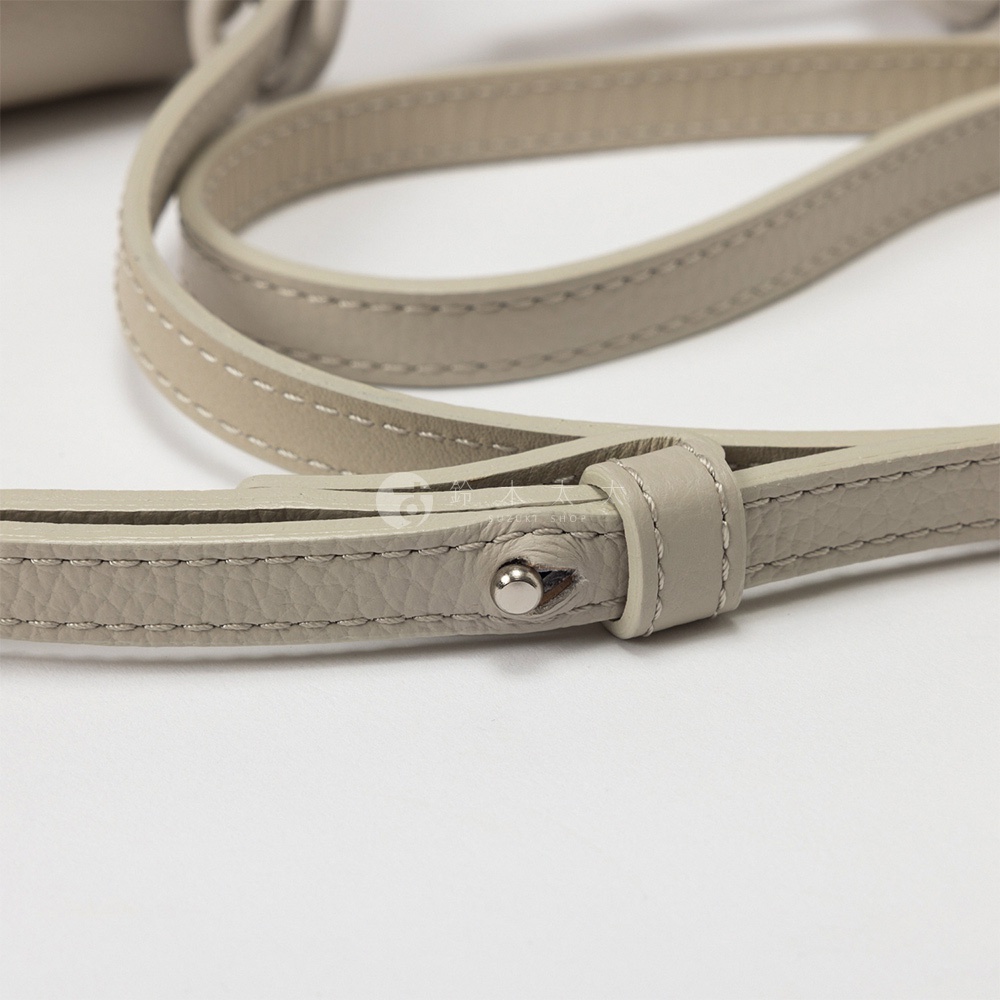 灰褐色皮革肩帶特寫，帶有金屬鈕扣和縫線細節