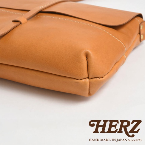 HERZ 手工皮革包，特寫部分展示了包包的縫線細節與材質質感，下方有品牌標誌與「HAND MADE IN JAPAN Since1973」字樣。