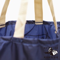 深藍色環保折疊收納購物袋，配有米色織帶提把，袋內有網格紋路和部分圖案，右下方有「犬印鞄製作所」的品牌標誌。