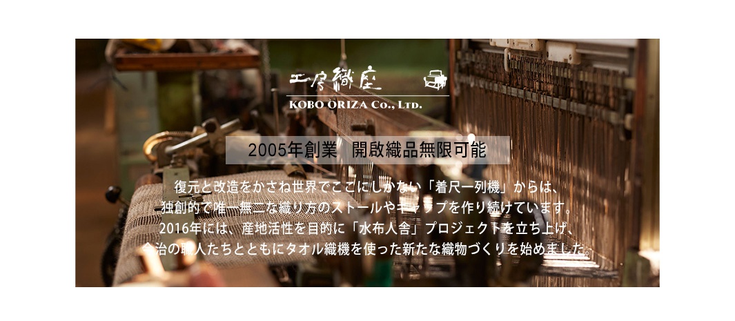 老式織布機，展示紡織細節，上方有日文品牌名稱「工房織座 KOBO ORIZA Co., Ltd.」及「2005年創業 開啟織品無限可能」字樣。