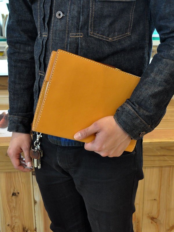 職人手作皮革A5筆記本書套，焦糖棕色，以白色車線裝飾，皮革質感，由人持握。