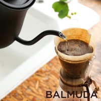 黑色手沖壺正將水注入裝有咖啡粉的濾紙杯中，水流細長，展現手沖咖啡的過程。