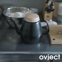 霧黑色琺瑯手沖壺，搭配淺褐色圓形壺蓋，壺身呈錐形，帶有細長彎曲的壺嘴和手把。