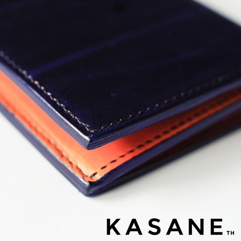 KASANE 品牌午夜藍Rugato皮革長夾，內裡為橘棕色植鞣牛皮，展現精湛手工縫線細節。