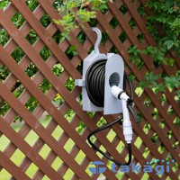 灰白色壁掛式水管收納架，裝有黑色水管，架上附有白色和黑色噴嘴。