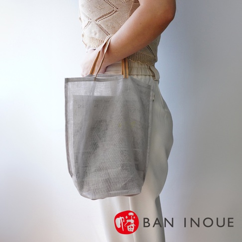 淺灰色網狀提把收納袋，可見透氣材質，搭配米白色衣物，展現簡約風格。