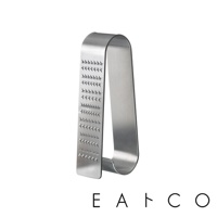 日製立式磨泥器，由不鏽鋼製成，呈現銀色金屬光澤。磨泥器呈U形，一側帶有多排銳利的磨齒，可用於磨細食材。