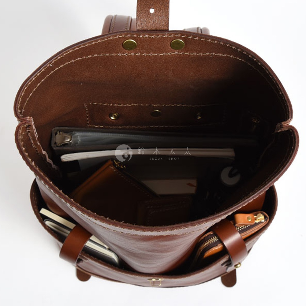 棕色皮革雙口袋折蓋後背包，內部可見文件夾、筆記本、錢包和拉鍊小包。
