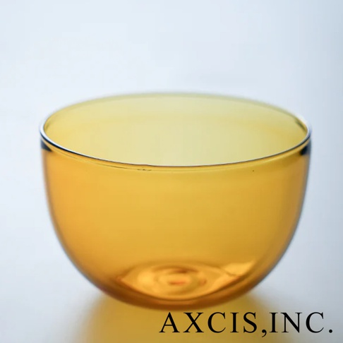 一個琥珀色透明玻璃製成的圓潤點心碗，碗身光滑，邊緣略有反光。