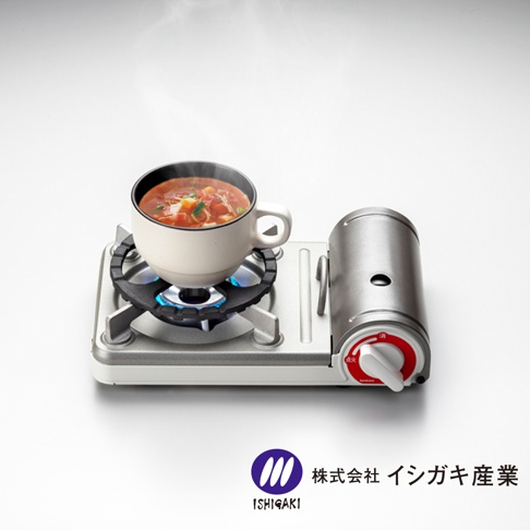 銀色與白色組合的五德瓦斯爐架，爐架上放置著一個裝有熱湯的白色陶瓷杯，爐頭火焰正在加熱。