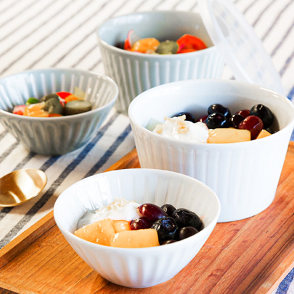 四件式陶瓷碗碟，帶有垂直凹槽紋理。有淺藍色和白色兩種顏色，碗內裝有水果和優格。其中一個白色碗配有透明蓋子。