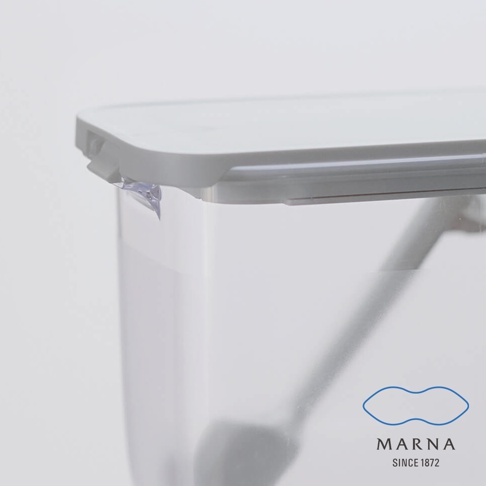 這是一張近距離特寫照，畫面展示了Marna密封防潮調味料盒的半透明盒身與白色盒蓋，邊緣處呈現細緻的密封設計，右下角印有藍色Marna品牌標誌與成立年份，整體風格簡潔清新。