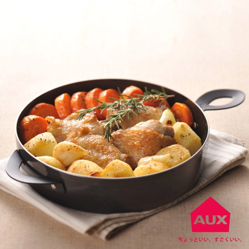 附蓋的黑色烤鍋中裝有烤雞塊、馬鈴薯塊和胡蘿蔔片，上方點綴著迷迭香。