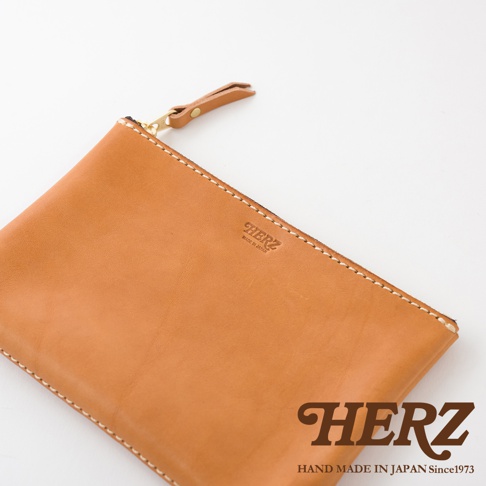 簡潔、描述性的替代文字（alt text）： 一個 tan 色皮革製成長方形拉鍊收納包，帶有同色系皮革拉鍊頭和金屬拉鍊。包面上壓印有品牌標誌。