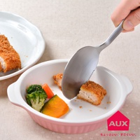 不鏽鋼切切分食匙，匙緣有鋸齒，正用來分切炸豬排，旁有花椰菜、紅蘿蔔塊與南瓜塊，盛裝於粉色陶瓷烤皿中。