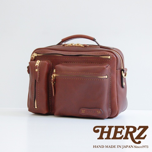 棕色皮革兩用多功能收納單肩包，設有頂部提把、多個拉鍊口袋及金屬拉鍊。包身前方有品牌標誌。