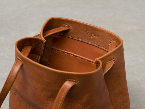 棕褐色皮革抽繩肩背手提托特包，包口處壓印有「Organ」字樣，有提把和抽繩設計，細節處可見縫線。