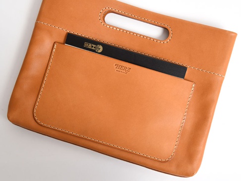 職人手作的淺棕色皮革橫式收納袋中袋，有兩個外層口袋，一個較大，一個較小，袋子上方有手提開口，縫線清晰。