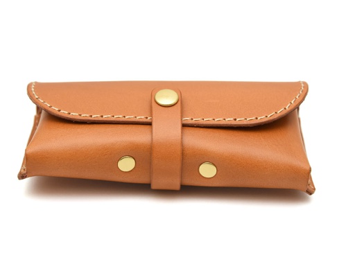 棕色皮革製成的眼鏡收納盒，附有金屬釦帶，側邊有兩個金屬釘，縫線明顯。