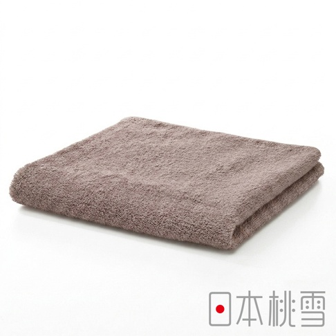 一條平整對摺的淺咖啡色日本桃雪精梳棉飯店毛巾，呈現柔軟細緻的毛圈質感，放置在純白色背景上，右下角印有日本桃雪的品牌圖標與文字。