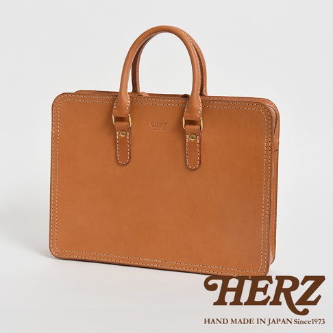 職人手作皮革手提商務公事包，卡其色皮革，簡約方形設計，配有雙提把和金屬扣件，邊緣有白色縫線裝飾。