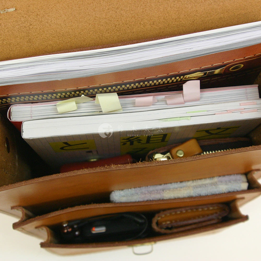 職人手作皮革單肩兩用小方包，棕色皮革，內部有筆記本、筆、錢包和鑰匙。