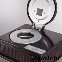 生豆烘焙機 MR-120，頂部開啟，露出銀色烘焙槽，烘焙槽上方有金屬網格。機身為深紫色，帶有散熱紋路，正面有警告標示。