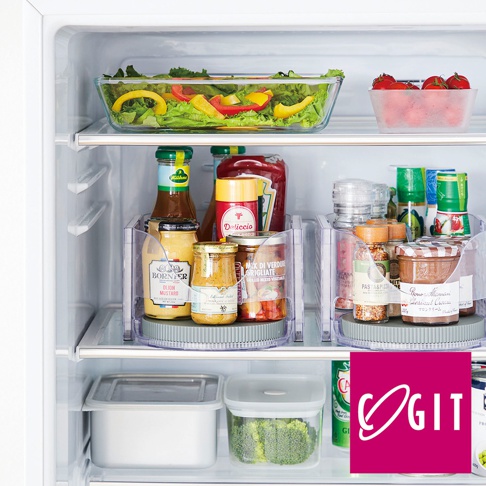 透明旋轉收納盤中擺放著多瓶醬料、調味品和罐頭，盤底為灰色圓盤。收納盤後方冰箱架上，有一個裝有沙拉的玻璃盤和一小盒番茄。