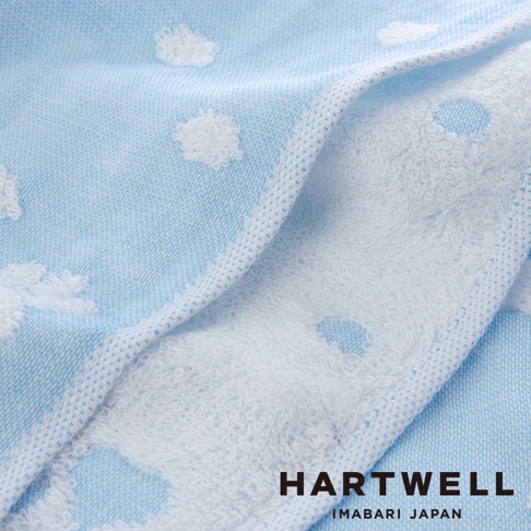 淺藍色今治純棉點點紗布毛巾，織有白色蓬鬆的點狀圖案，毛巾邊緣有白色網格滾邊，展現柔軟的織物紋理。