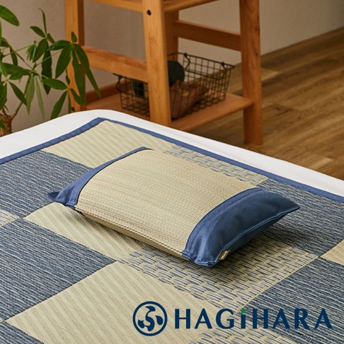 藺草編織枕頭，以藍色布料包覆兩側，置於格紋藺草墊上。