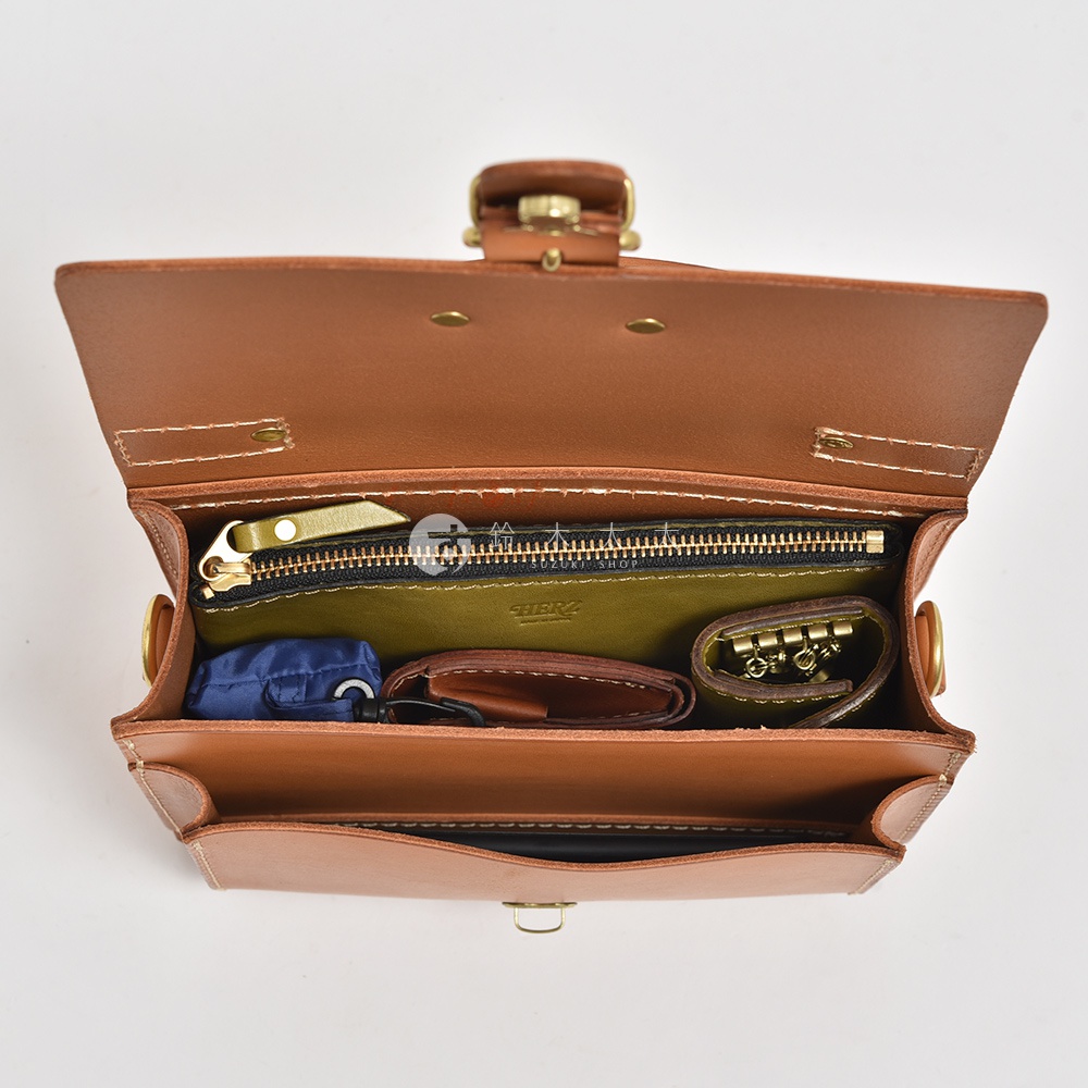 職人手作皮革經典混合風迷你單肩包，棕色皮革材質，包內有綠色內襯拉鍊袋、藍色物品、鑰匙包和咖啡色皮夾。