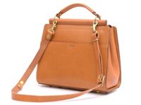 一個棕褐色皮革製成的兩用單肩包，帶有頂部提把、可拆卸肩帶和黃銅色五金配件，包身縫線清晰可見，正面有品牌壓紋。